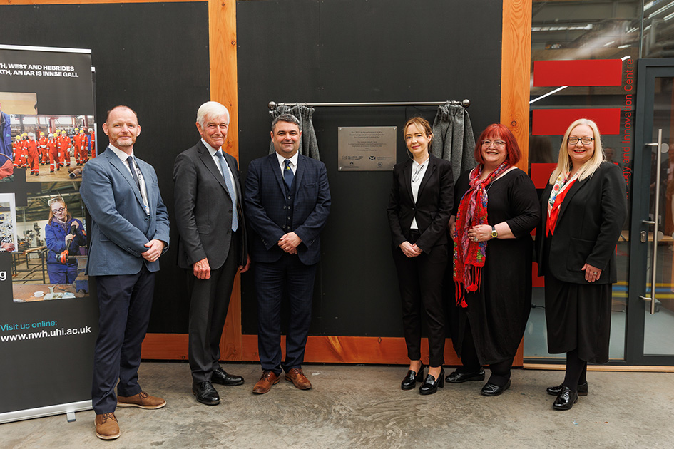 Six people stood in front of a plaque